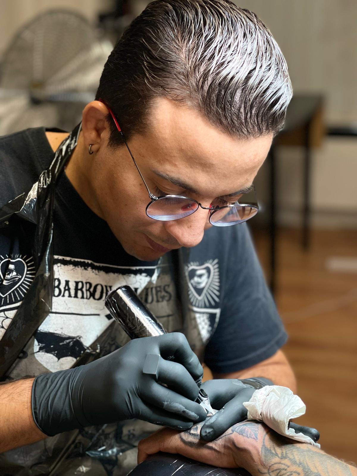 Rafael Amaro, dit Kako, concentré sur l’exécution d’un tatouage