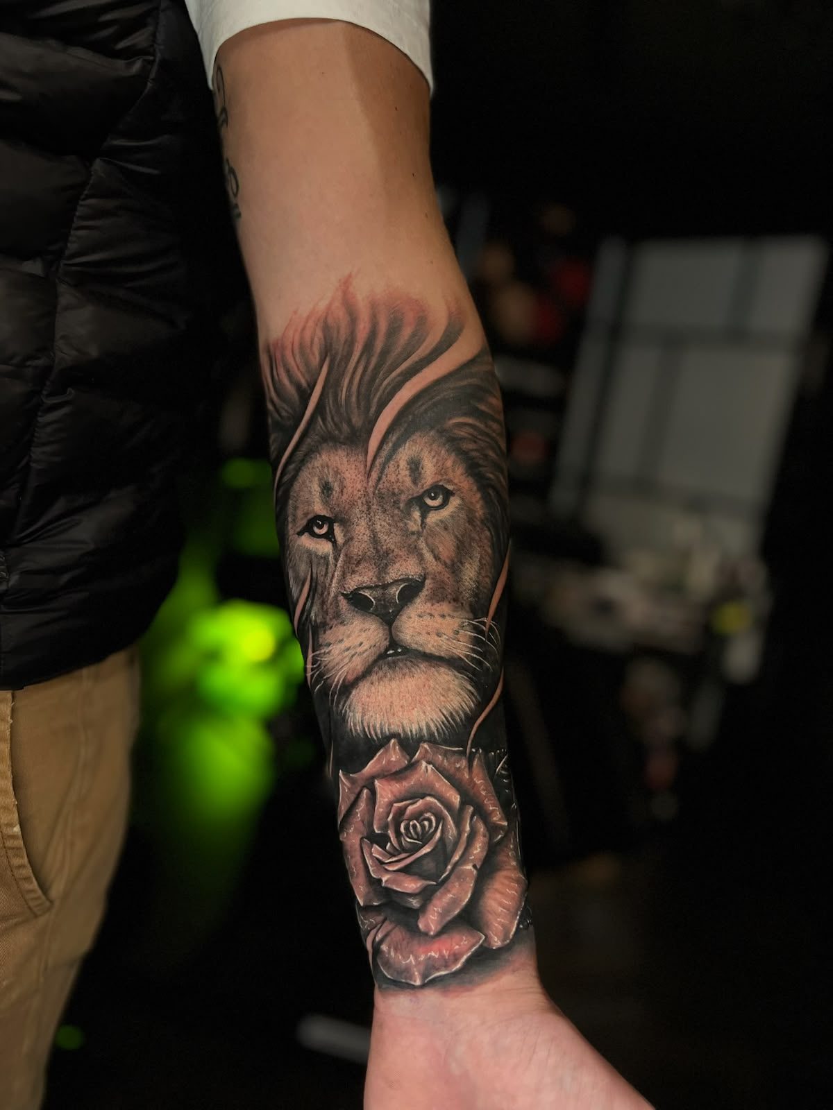 Tête de lion et rose en réalisme noir et gris sur l’avant-bras, par Kako Tattoo à Genève
