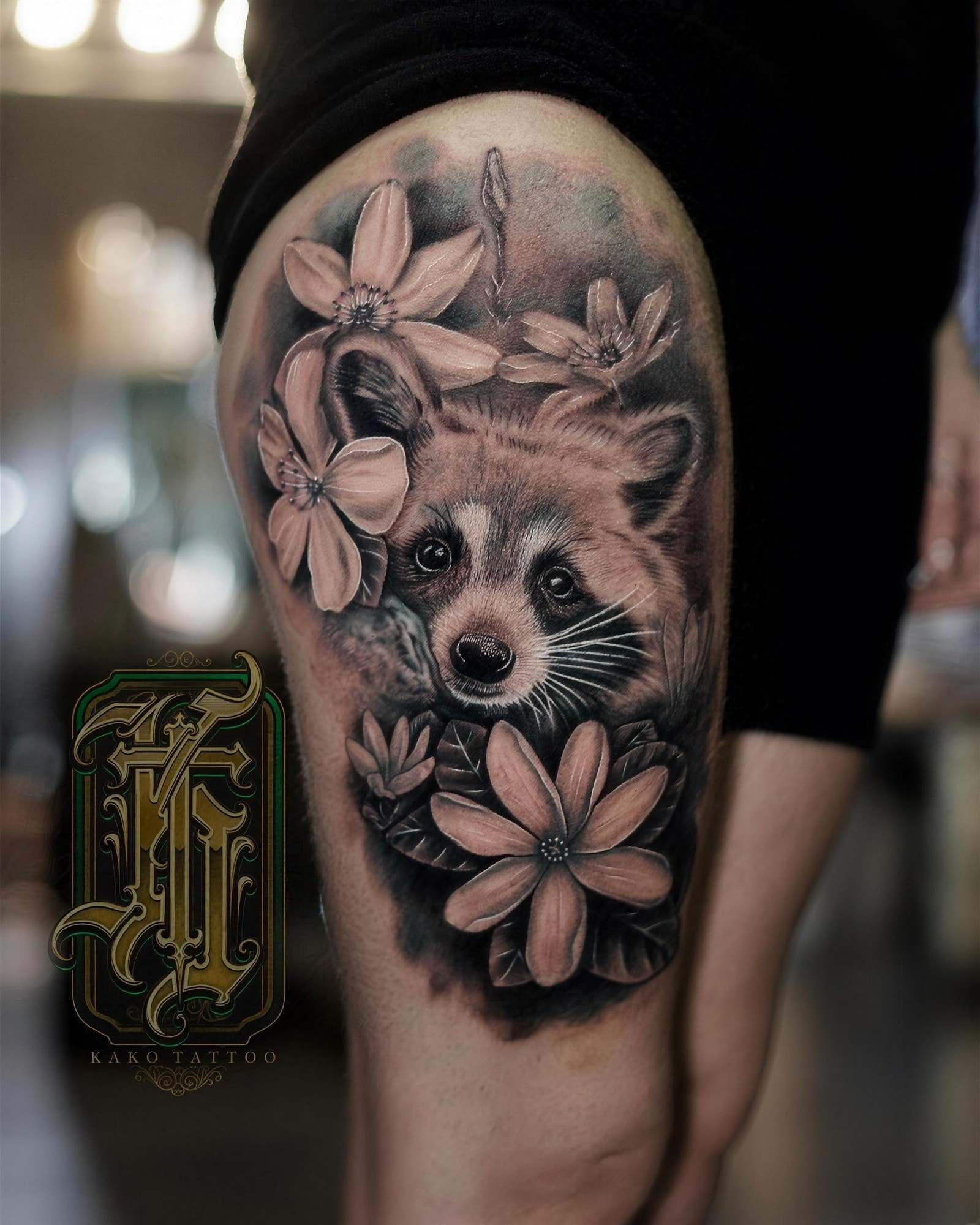 Raton laveur et fleurs en réalisme noir et gris sur la cuisse, par Kako Tattoo à Genève
