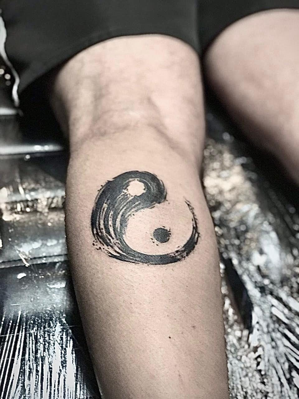 Yin-yang tracé au pinceau en blackwork sur le mollet, par Kako Tattoo à Genève